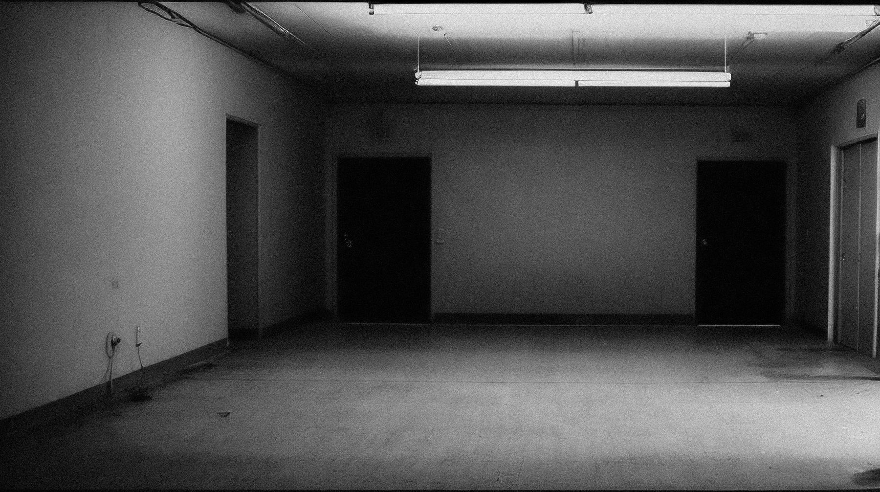 Kitchen as a bare shell: grey screed, bare walls and two dark service openings.